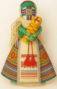 Motanka : poupées d’espoir, tissées de paix 1 Poupée traditionnelle ukrainienne Motanka en tenue colorée, symbole de protection et d’espoir, tenant un bébé dans ses bras.