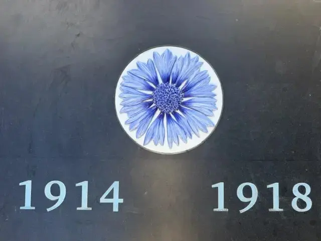 Médaillon de bleuet en faïence de Limoges encadré des dates 1914 et 1918 sur le monument aux morts